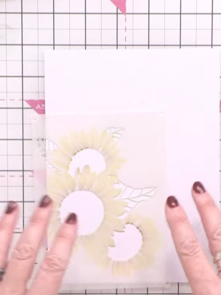 Step 3: Position the second stencil layer over your card to show the sunflower centre and leaves. Apply ground espress