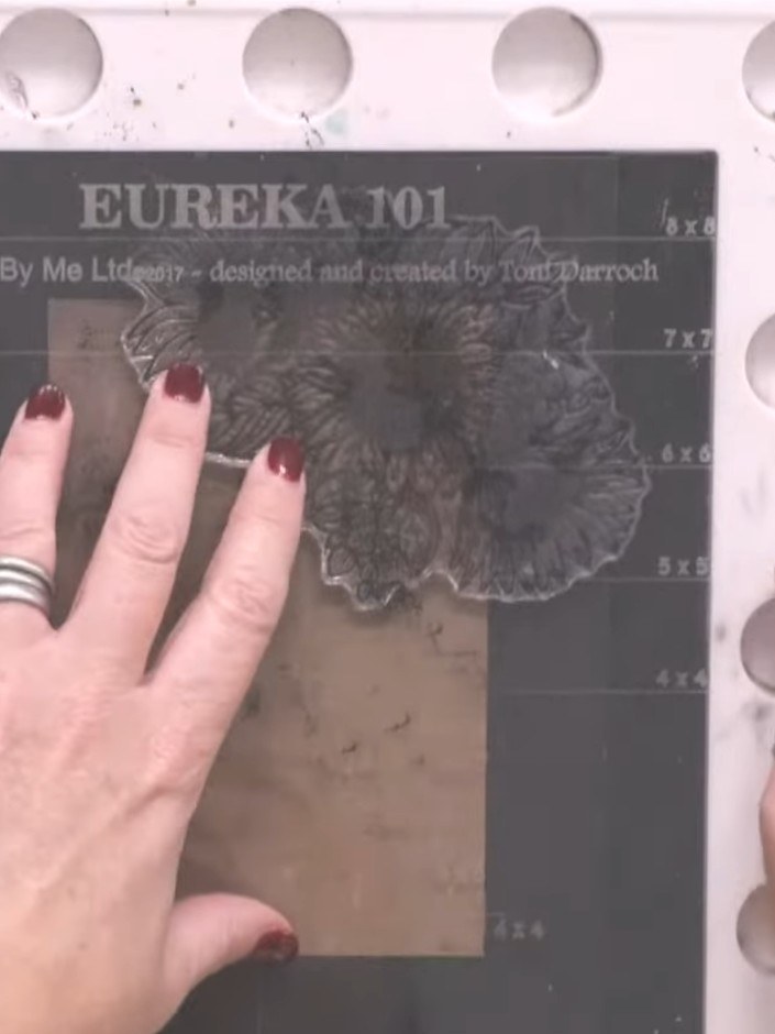 Step 1: Position the Eureka 101 A6 stamp in one corner of your dark card base. Hold it in place ready for the next ste