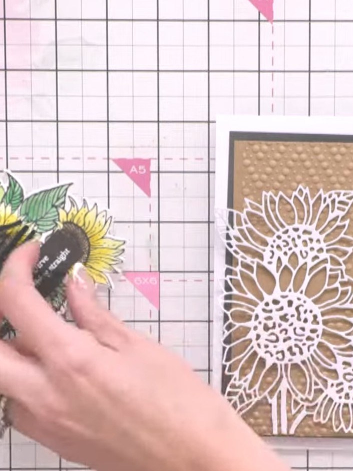 Step 5: Optionally apply rub-on embellishments to enhance the design, positioning them to sit within the embossed sunf
