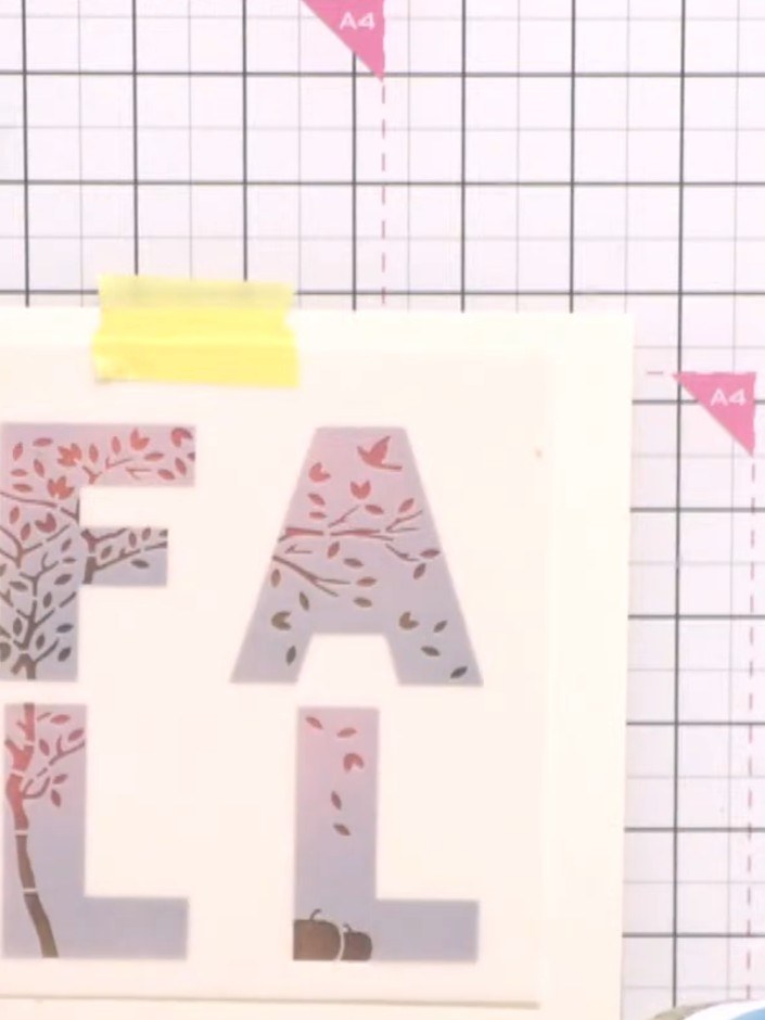 Step 2: Position the overlay stencil (showing the foliage and branches pattern) over the dried base letters. Use the r