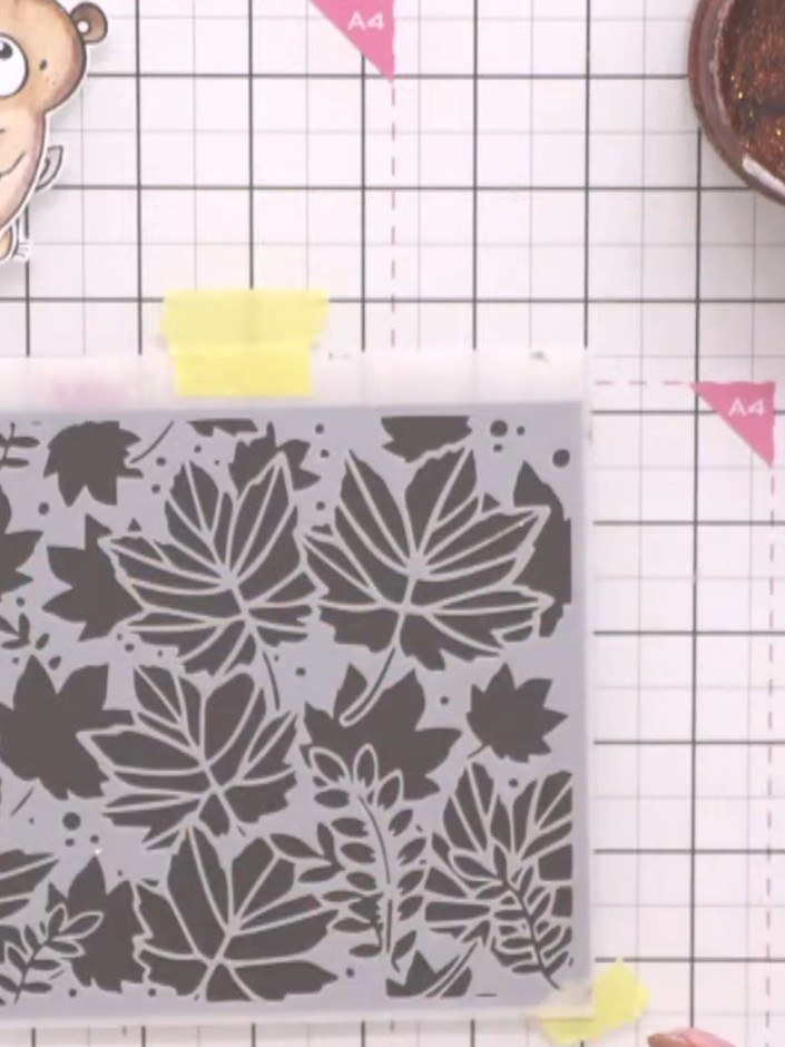Step 1: Position the 6x6 inch leaf stencil on dark brown cardstock and secure it in place with masking tape at the top