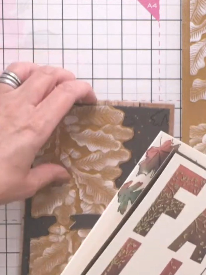 Step 7: Adhere the layered sentiment banner to the card front, positioning it across the embossed oak leaf design.