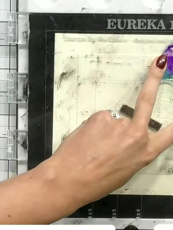 Step 8: Carefully lift the stamp away from the card to reveal the watercolour floral design with purple, blue and gree
