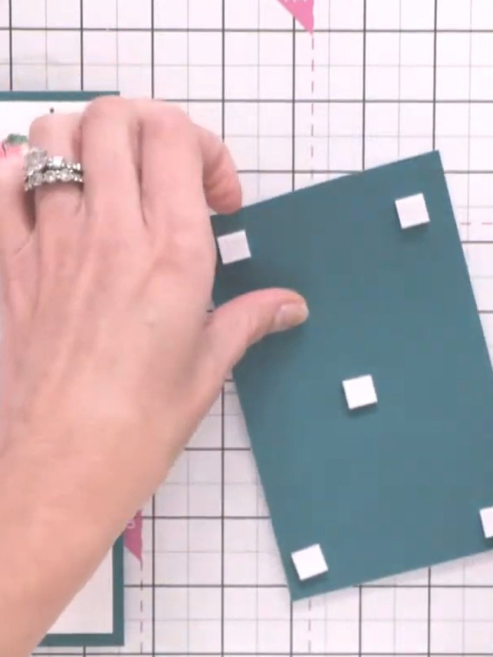 Step 11: Adhere the completed layered panel with foam pads to a teal folded card blank to finish your card.