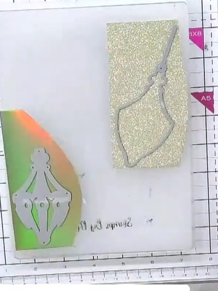 Step 4: Layer the decorative die-cut element on top of the gold sparkle bauble front, positioning it carefully and adh