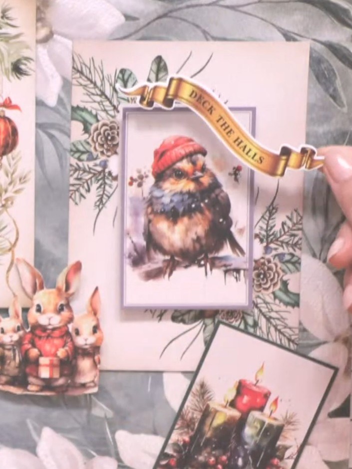 Step 6: Add the decorative banner sentiments to your cards. Position 'Deck the Halls' on the top left card with the ph