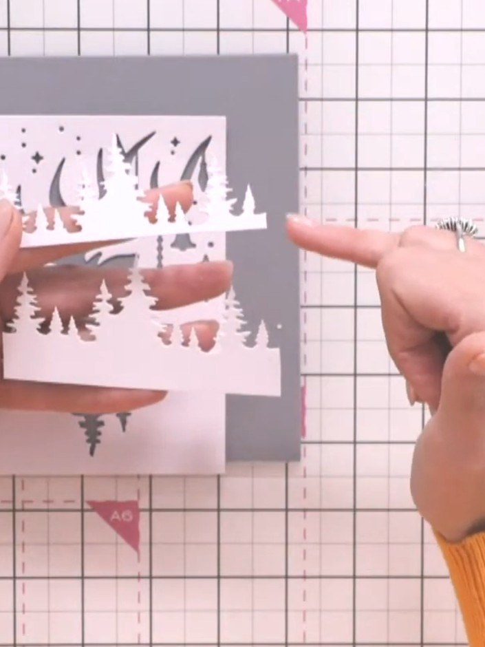 Step 3: Die-cut the tree silhouettes from white card stock using the stencil. Keep the die-cut pieces attached at the 