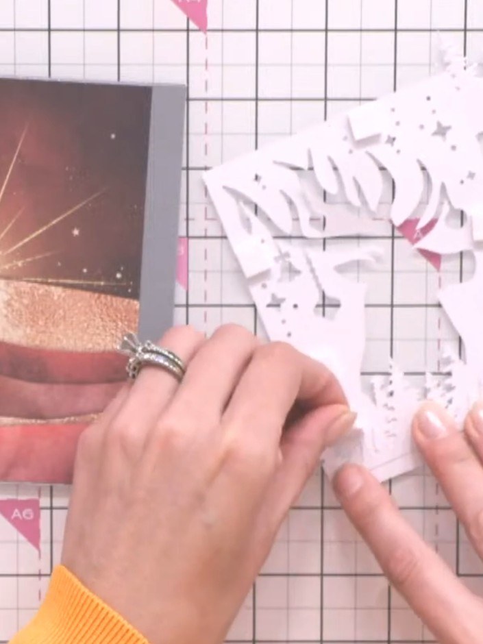 Step 8: Layer the white tree die-cuts at varying heights behind the silhouette panel using foam pads to create a dimen