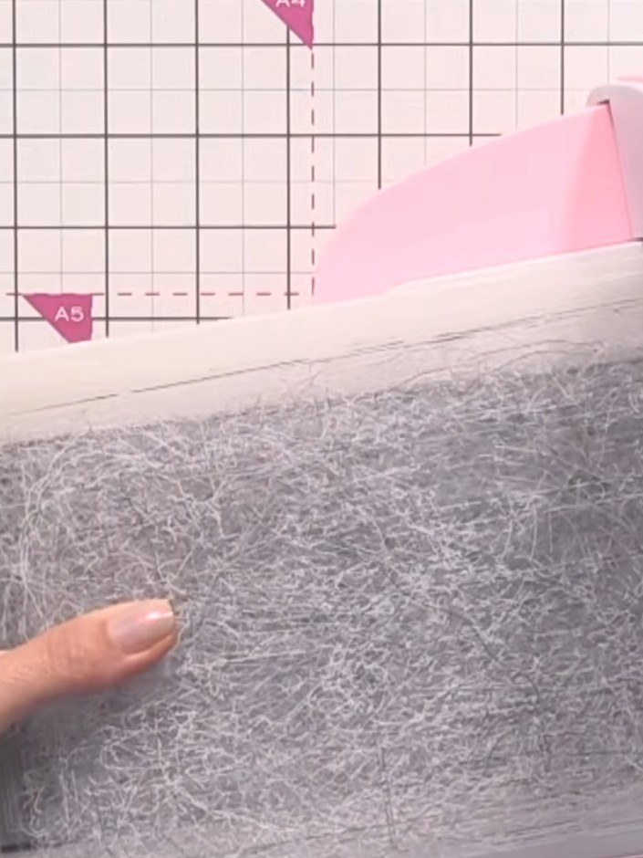 Step 1: Cut a piece of black cardstock and place it into the embossing folder. The embossing folder shown has a textur