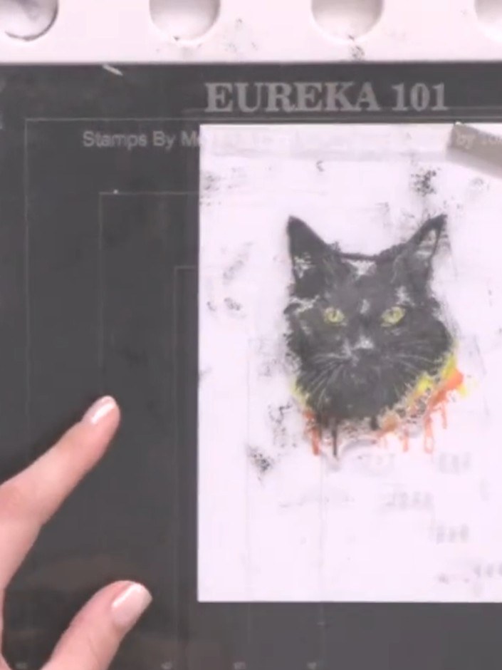Step 8: Stamp a sentiment such as 'Hocus Pocus' below the cat image using black ink. Position the sentiment stamp cent