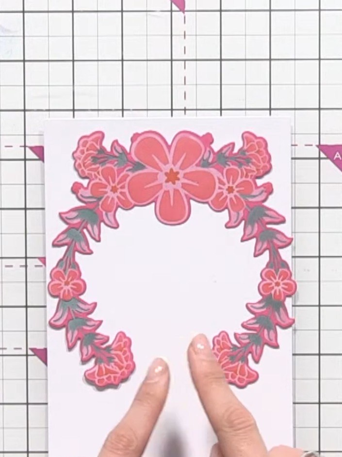 Step 10: Mount the pink floral wreath die-cut onto a white card base, positioning it centrally to create your finished 