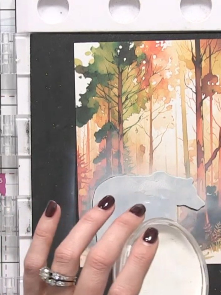 Step 6: Using a brush, apply white gesso or watercolour paint to create falling snow effects across the forest scene a