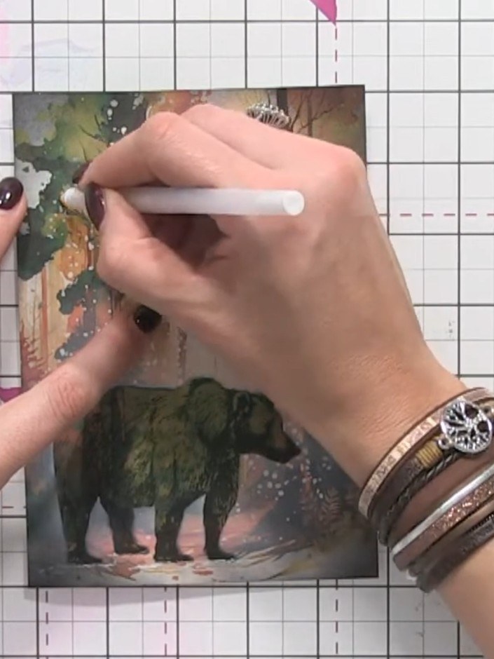 Step 9: Using a white gel pen, add highlights to the bear's feet and tree details to ground the image and create spark