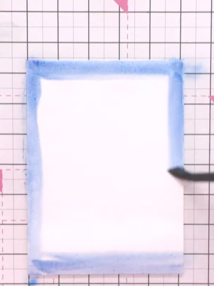 Step 2: Apply ocean blue ink to the edges of the wet card using circular motions, working from the edges towards the c