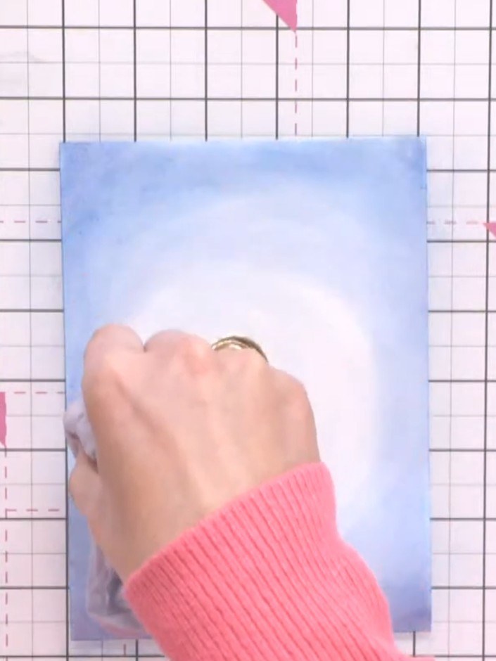Step 5: Using a damp brush or tissue, blend darker blue colour around the edges of the card to add depth and dimension
