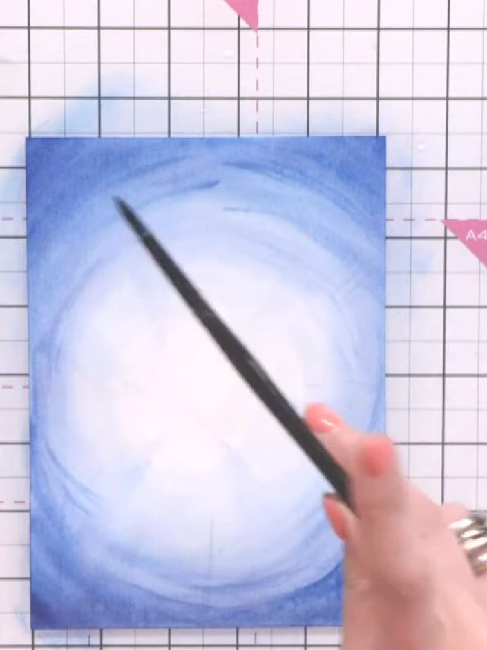 Step 7: Splash clean water across the damp blue background using a loaded brush to create a speckled ripple and wave e