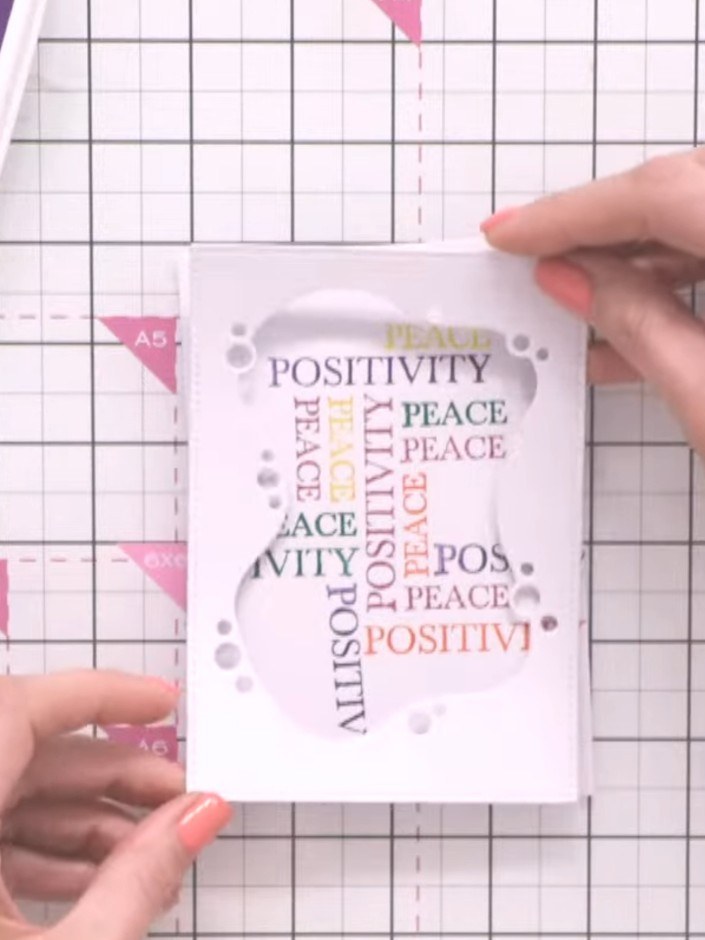 Step 9: Position the stamped word background card behind your die-cut frame, ensuring it's straight and centred. Secur
