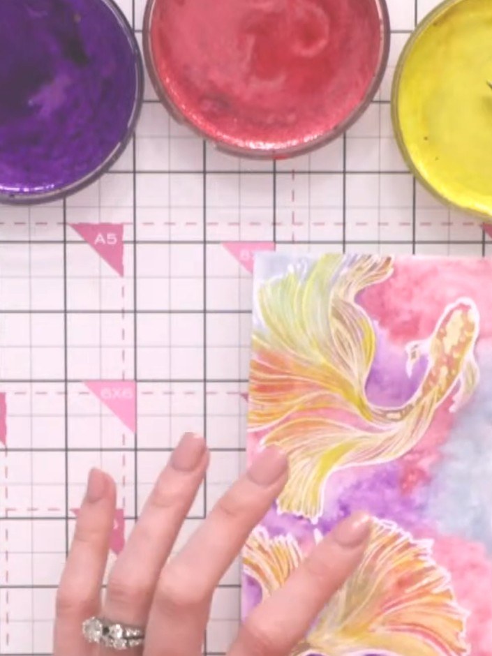 Step 13: Create splatter details by loading a brush with watercolour and holding it high above the card to create large