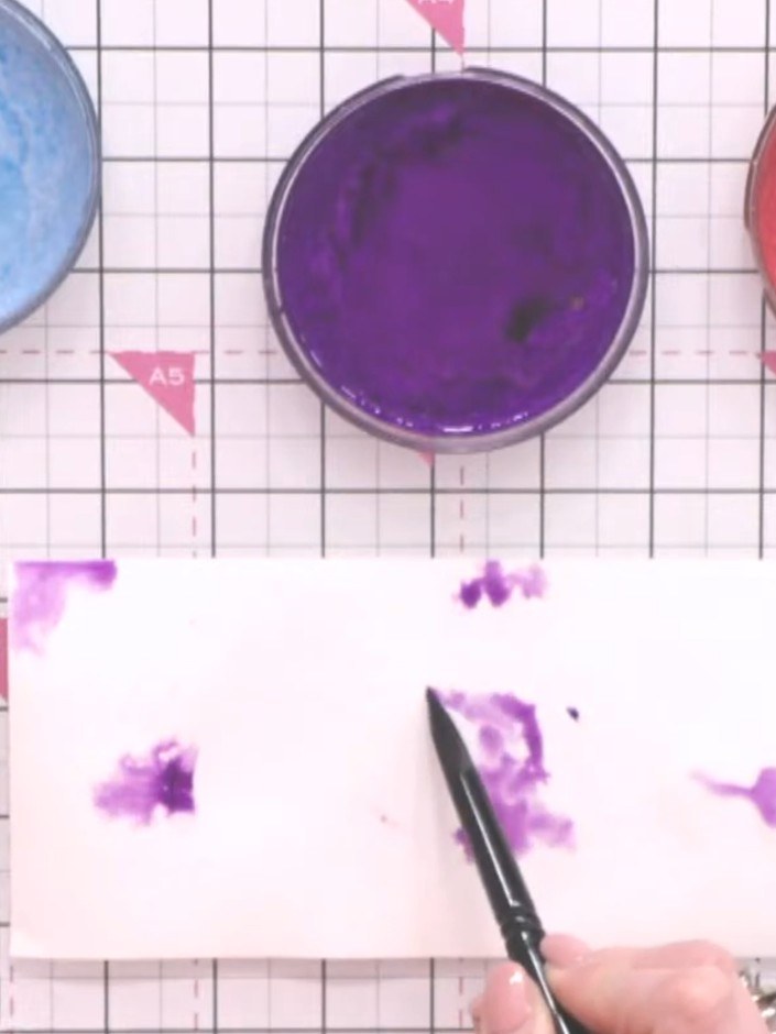 Step 8: Apply purple ink to the wet watercolour paper using a brush, allowing the colour to spread naturally across th