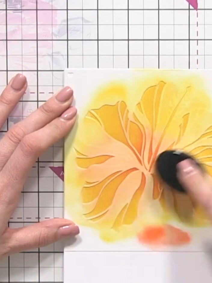 Step 6: Using stencil number one again, apply pink ink to the tips of the yellow petals with a blending sponge. This a