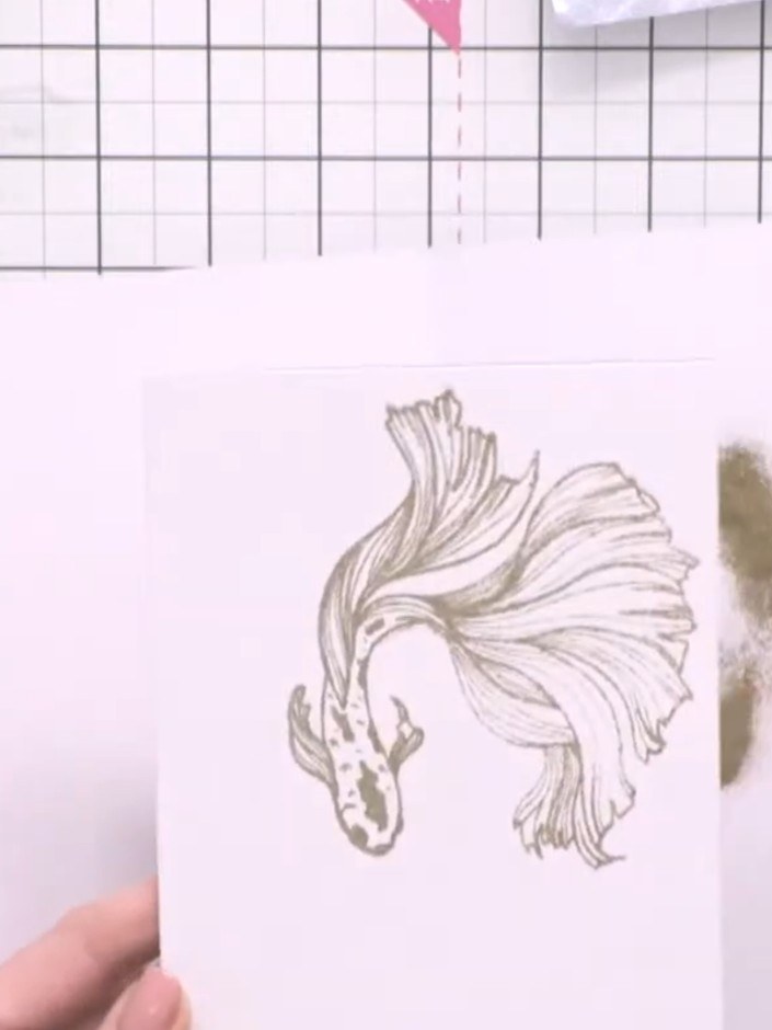 Step 3: Apply gold embossing powder to the inked fish stamp. Heat set with a heat tool until the powder melts and beco