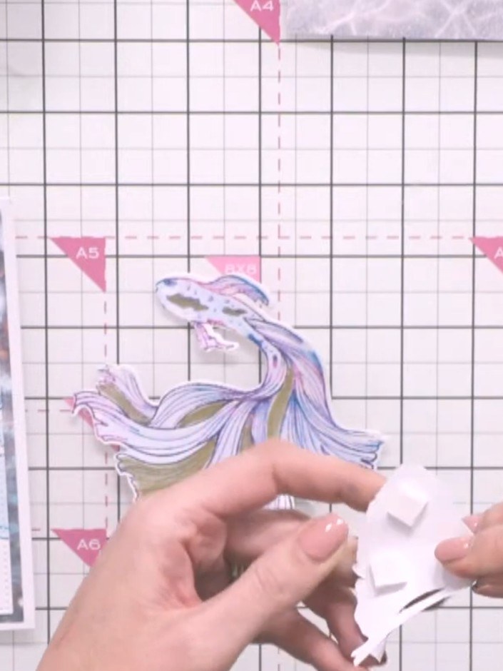 Step 10: Layer the tail piece onto the main fish body using foam pads to create height and dimension.