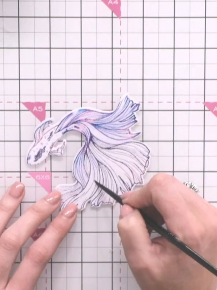 Step 6: Wet the fish with water using a paintbrush and drag the inked colours outward to create a watercolour effect. 