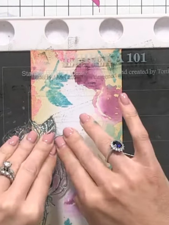 Step 11: Stamp the black detail layer over the dried watercoloured panel, carefully aligning it with the coloured flowe