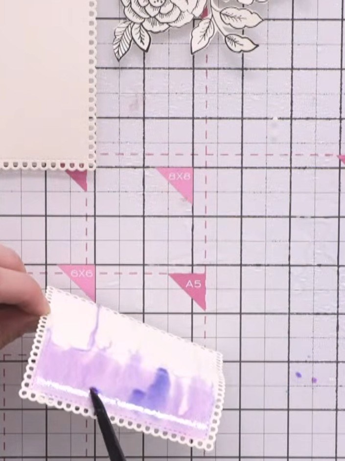 Step 7: Apply teal and pink ink to the wet surface, allowing the colours to blend and run together. Tap the card at an