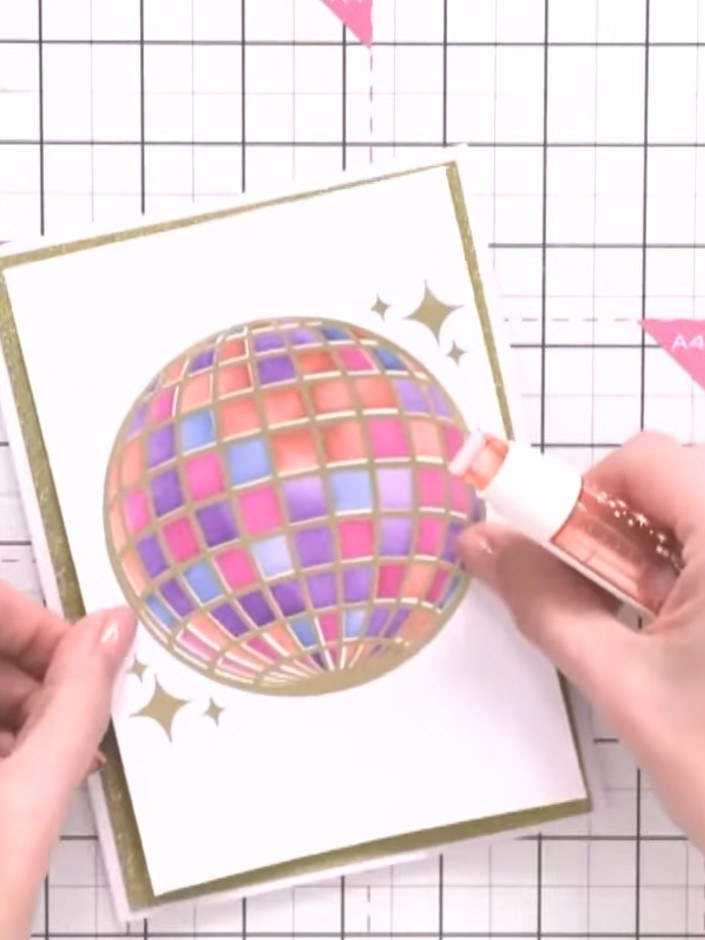 Step 5: Gold emboss the stamped disco ball design. Use a heat tool to melt the gold embossing powder until it creates 