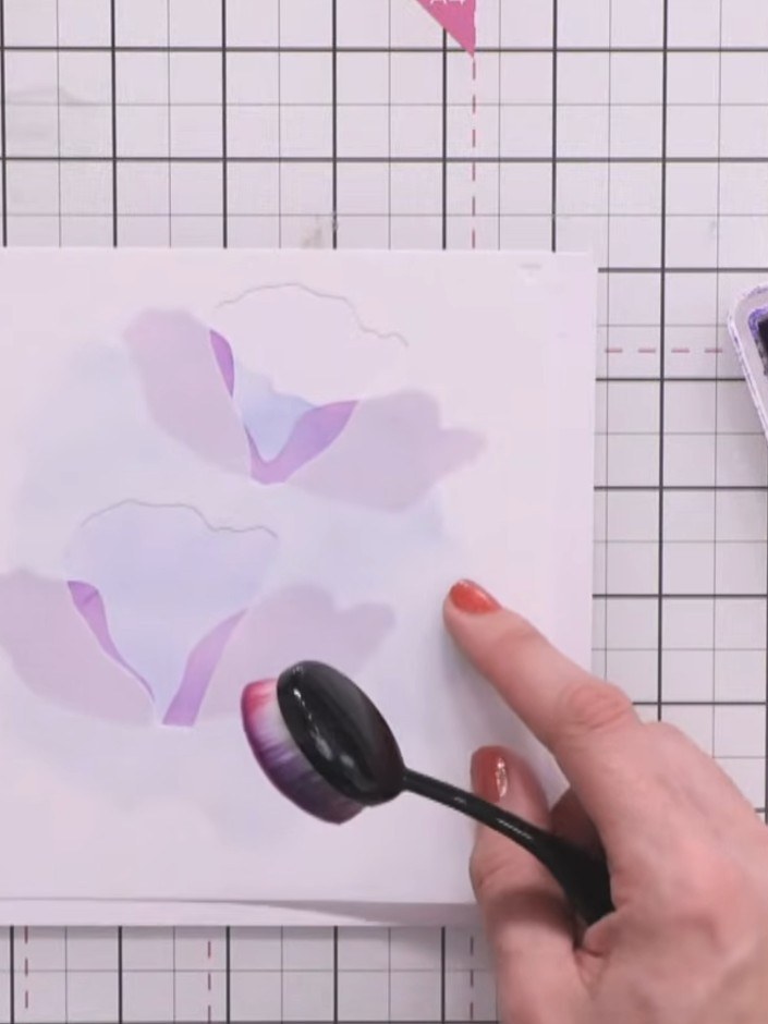 Step 5: Position the splat stencil randomly across the card. Use the ink pad to apply purple ink through the stencil o