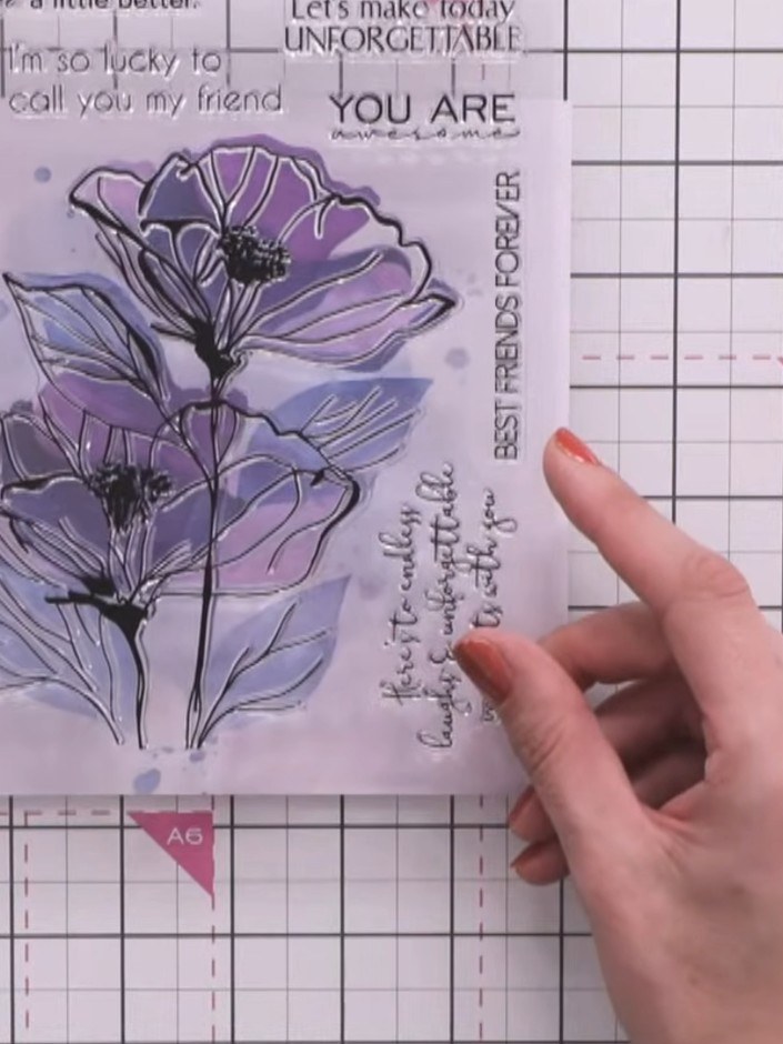 Step 7: Stamp the large poppy stamp in black ink onto the layered background, positioning it over the stencilled layer
