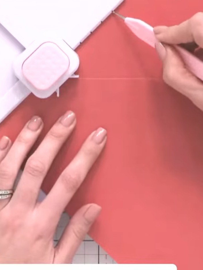 Step 4: Use the punch tool to create holes in the designated areas on the coral cardstock. Drag the tool all the way t