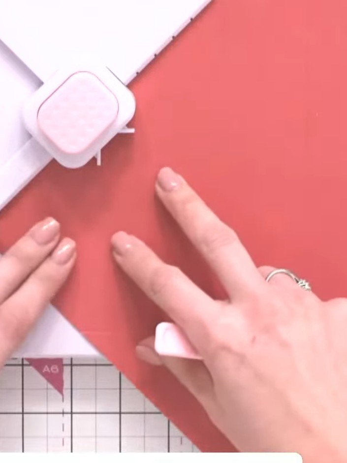 Step 6: Continue rotating the coral cardstock and repeat the scoring and punching process on all four sides. Use the s