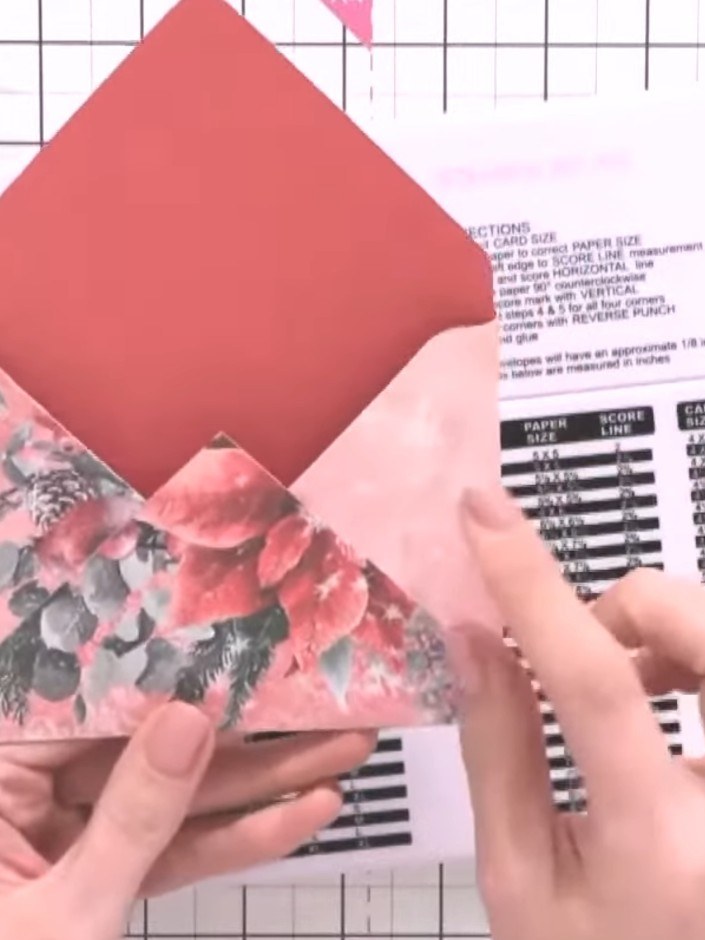 Step 9: Fold the coral envelope into its diamond shape. Insert the decorative hook and eye fasteners through the punch