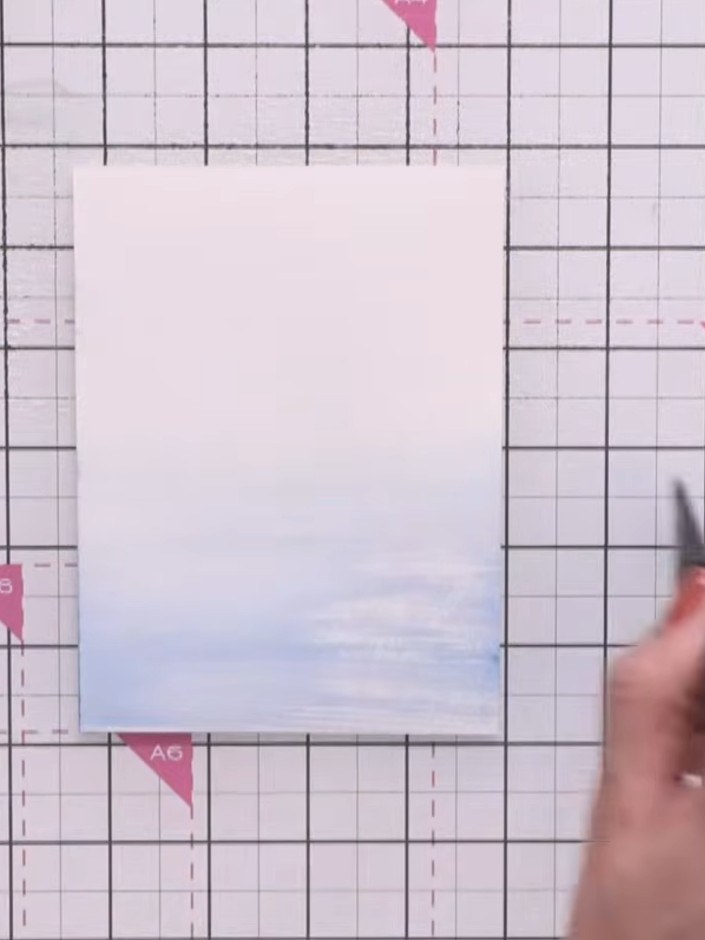 Step 2: Spray the inked card with water and blend the blue ink using horizontal brush strokes, working from light at t