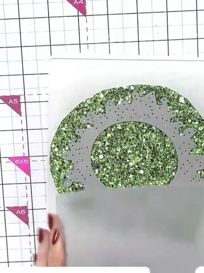Step 3: Take the two die-cut wreath pieces with green glitter and twist them together to create a fuller, more dimensi