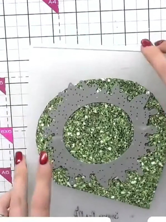 Step 5: Befestige den gedrehten Kranz auf einer Grundschicht aus grünem Glitzer-Cardstock. Platziere ihn mittig und kleb ihn fest.