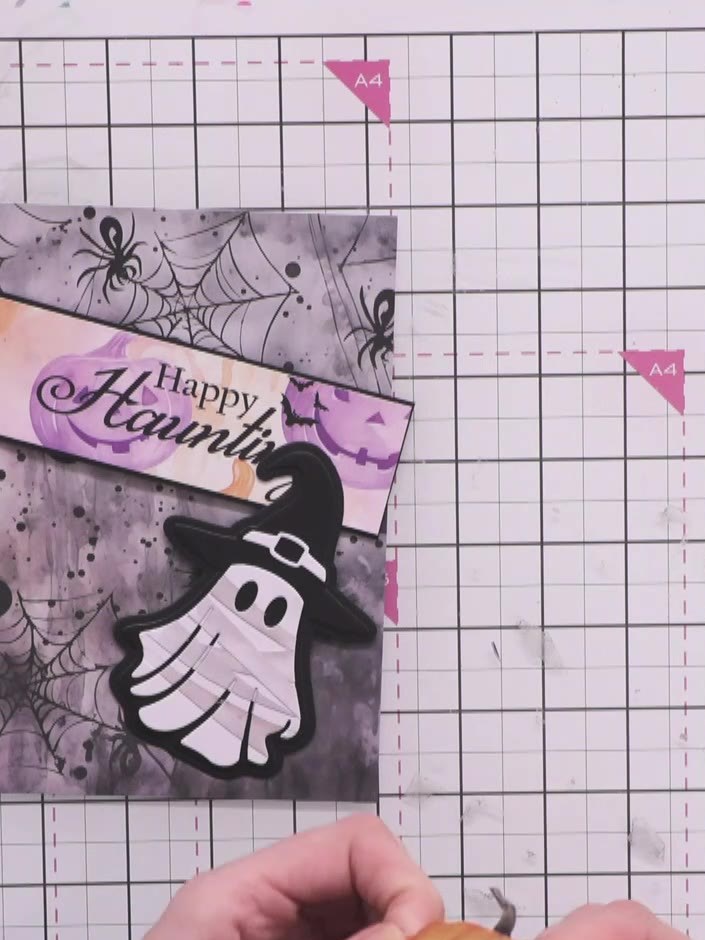 Step 12: Mount the 'Happy Haunting' sentiment banner diagonally across the top of the decorated card front. Position th