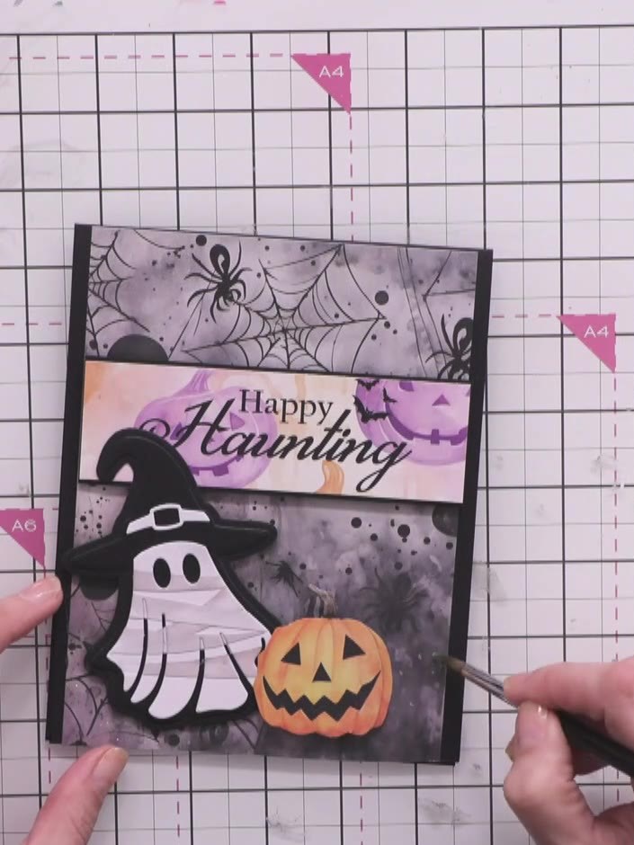 Step 15: Apply clear sparkle or glitter to the spiderweb details on the background paper to add shimmer and dimension t