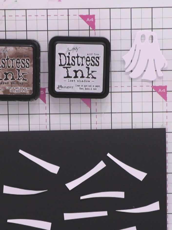 Step 7: Layer the distressed white strips onto the black ghost body to create a wrapped mummy effect. Arrange the stri