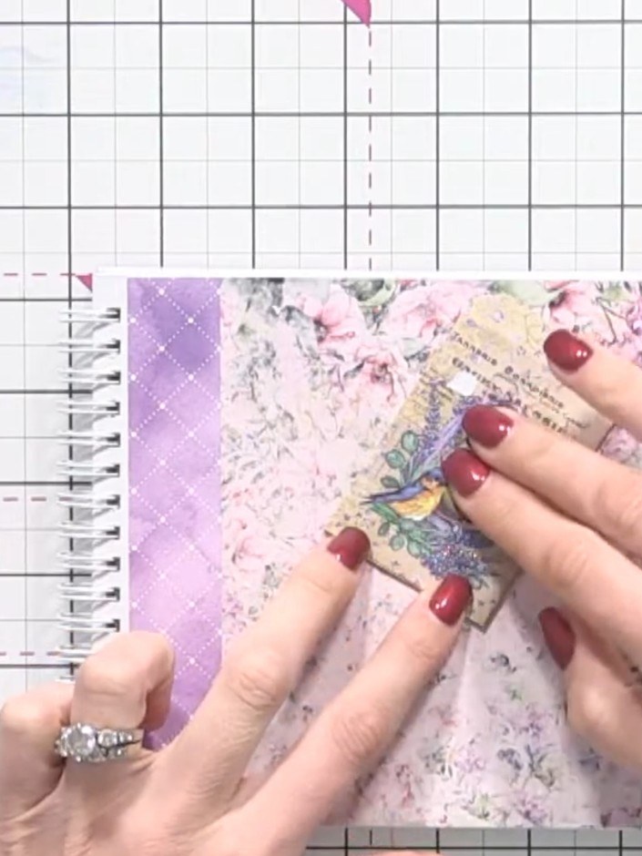 Step 6: Layer additional patterned papers and ephemera pieces from the pad onto the floral background. Position decora