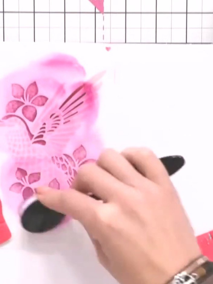 Step 6: Use stencil five with the same pink ink, pressing firmly to add deeper colour and dimension to the tail feathe