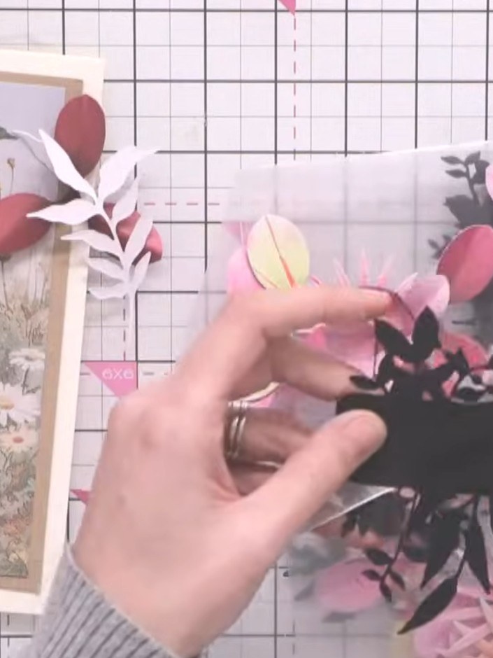 Step 11: Add complementary leaves and foliage from the die-cut floral sheet around the hellebore flower to complete the