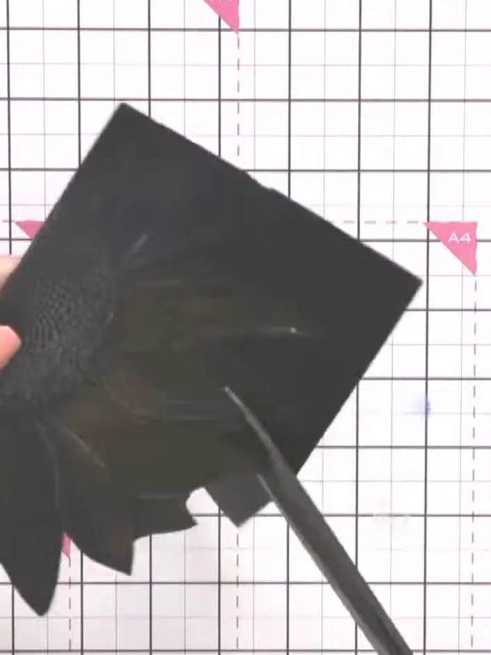 Step 7: Use scissors to carefully cut around the embossed sunflower design, trimming away the excess black card to cre