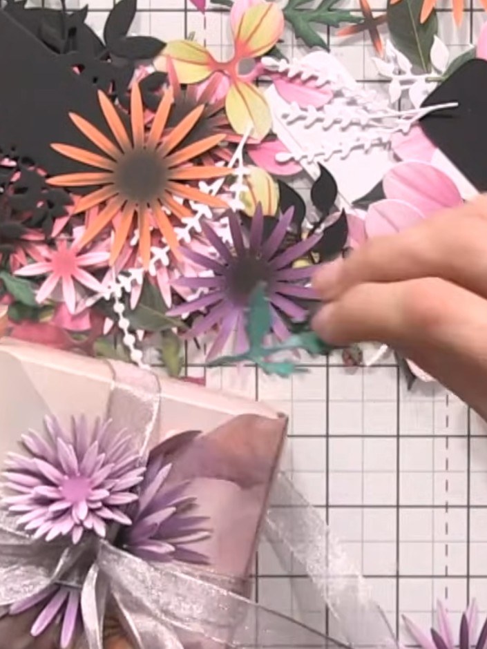 Step 10: Add foliage pieces and banner die-cuts between the flowers to fill gaps and create depth. Position the greener