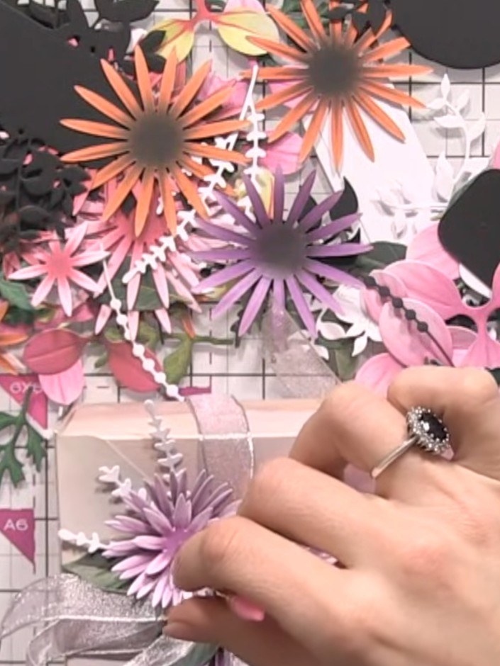 Step 11: Secure all floral elements to the gift box using a hot glue gun or adhesive pads. Ensure each purple chrysanth