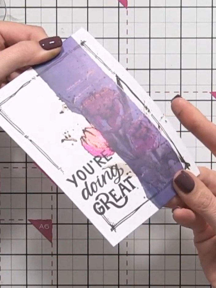 Step 2: Position the vellum piece on top of the white card panel with the 'YOU'RE doing GREAT' sentiment, aligning it 