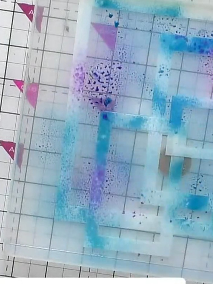 Step 2: Spray ink in blue and pink colours over the layered stencils to create a multi-coloured base. Work across the 