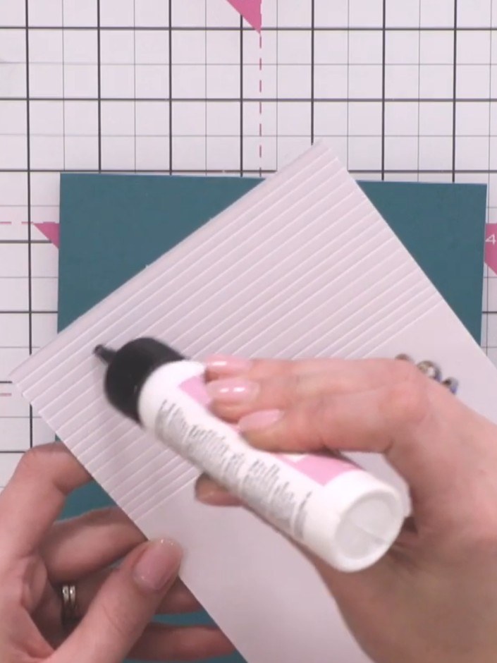 Step 5: Apply glue to the back of the white scored panel and adhere it to the teal card base, positioning it so the sc